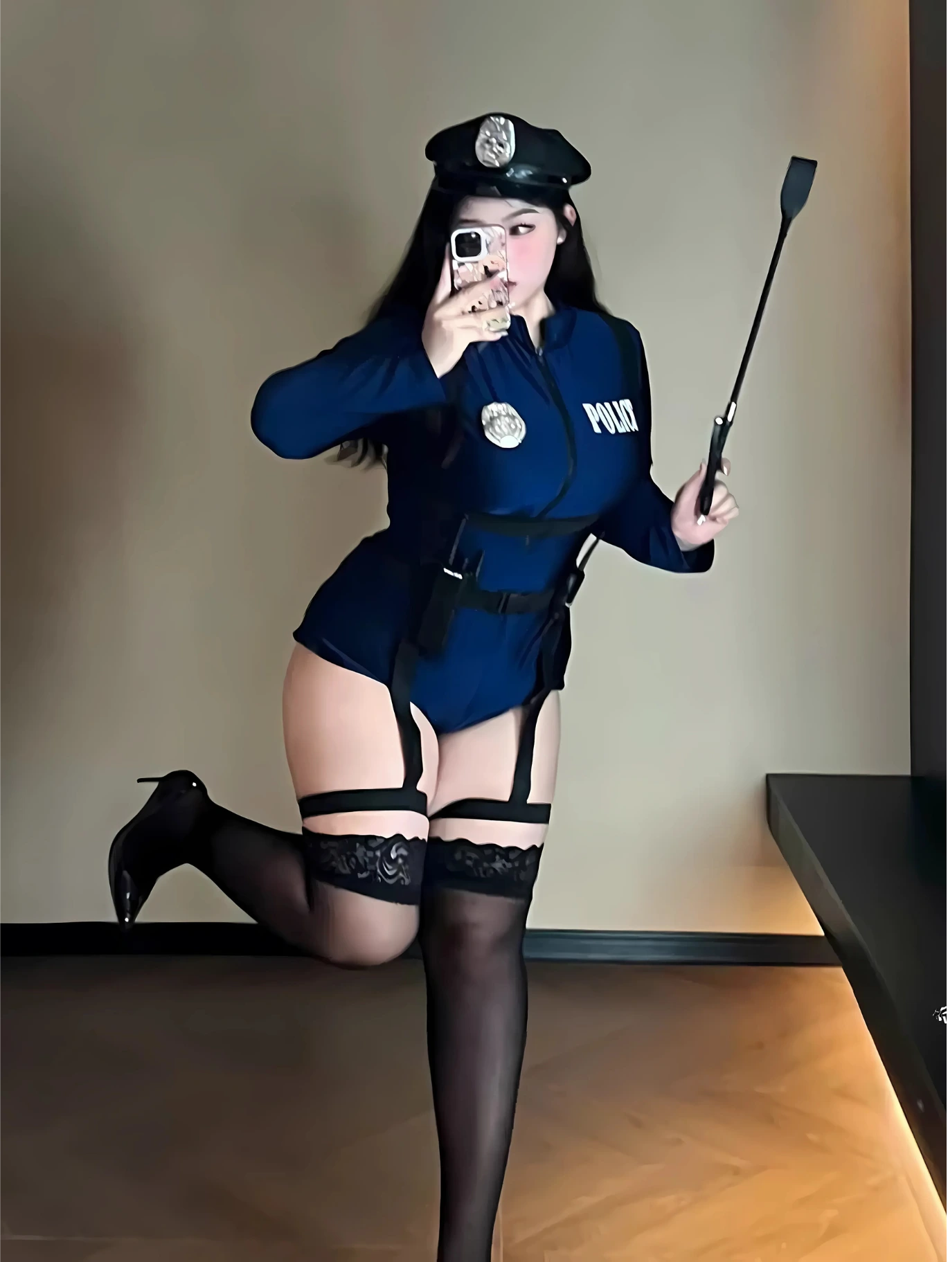 Curvy model in navy police cosplay lifting leg playfully, holding a black baton