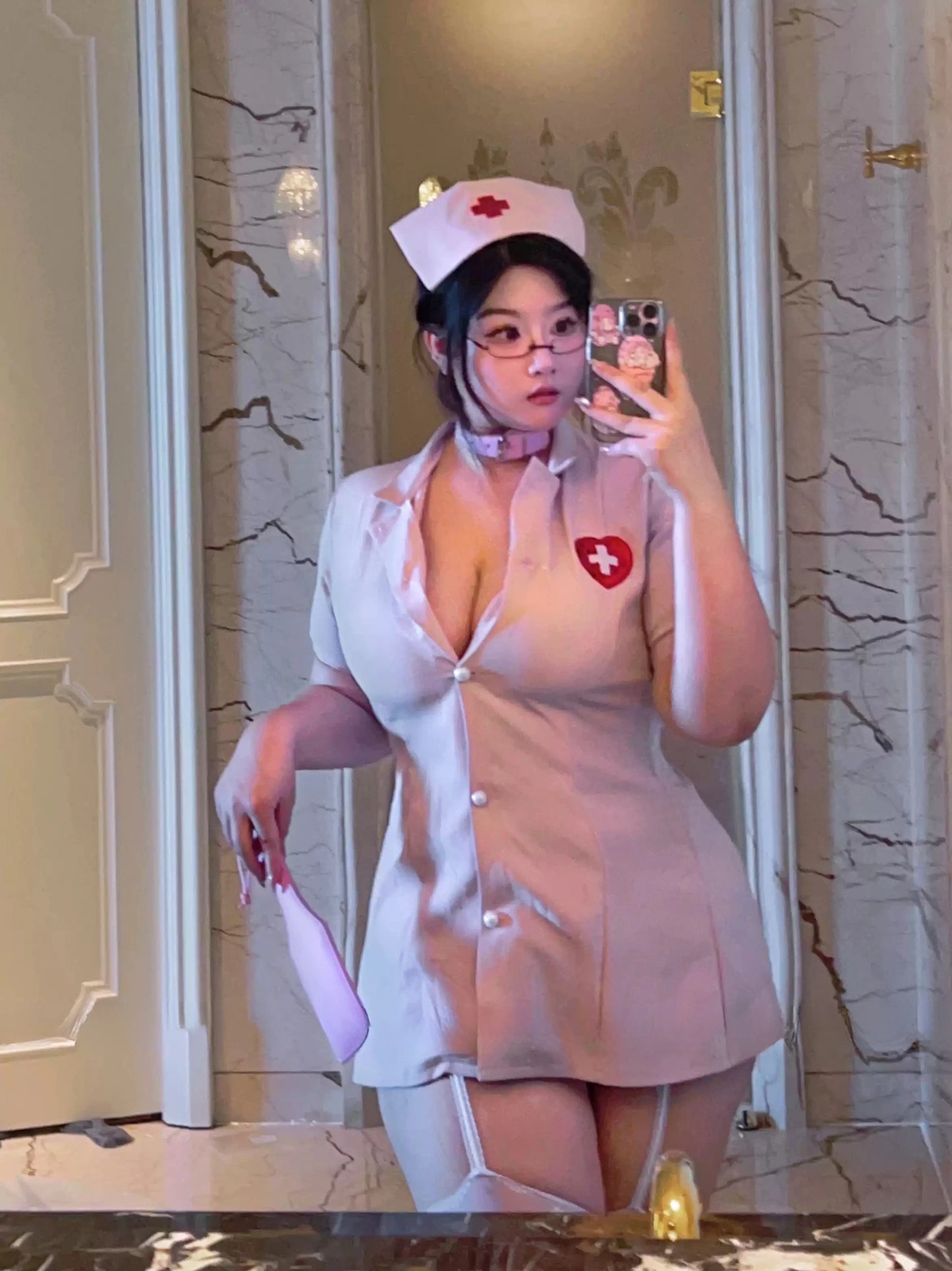 Plus size model wearing a pink nurse costume with matching cap and heart patch, posing in front of a mirror.